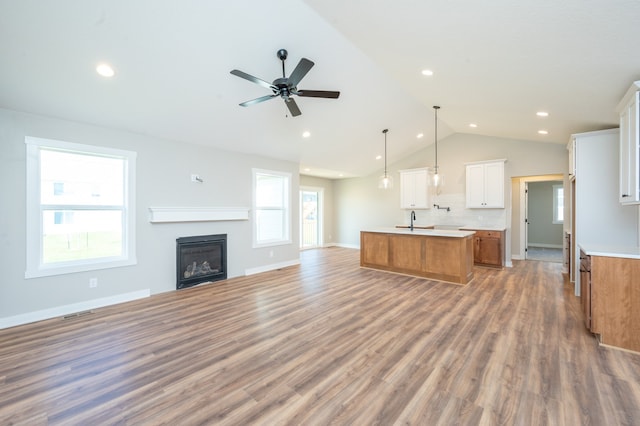 unfurnished living room featuring hardwood / wood-style floors, ceiling fan, sink, and vaulted ceiling