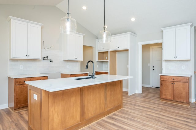 2640 Abbott Dr, Waukee, IA 50263 - kitchen featuring lofted ceiling, backsplash, a kitchen island with sink, light wood-type flooring, and pendant lighting