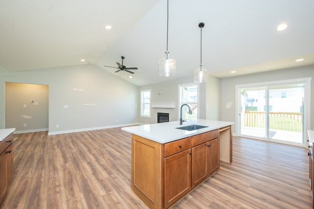 kitchen featuring light wood-type flooring, a center island with sink, sink, and vaulted ceiling