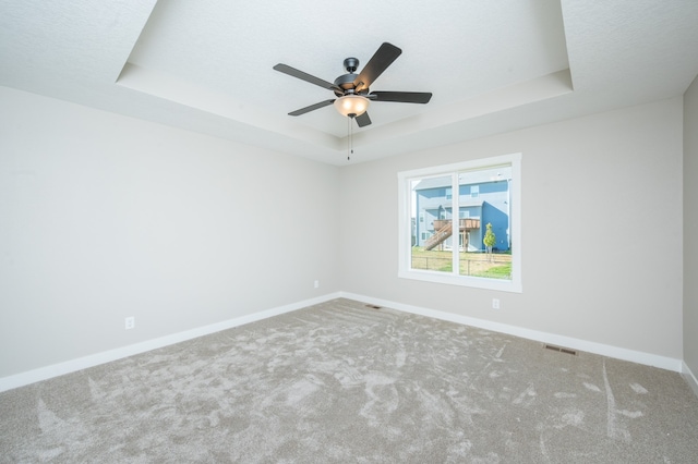 spare room with ceiling fan, carpet flooring, and a raised ceiling