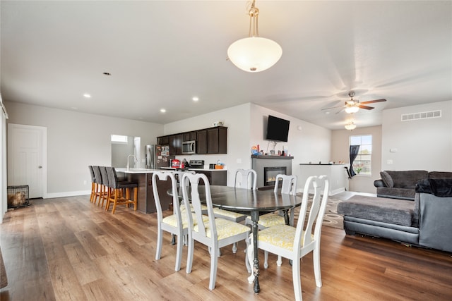 dining area featuring ceiling fan, sink, and light hardwood / wood-style flooring