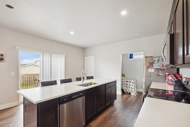 kitchen featuring appliances with stainless steel finishes, dark brown cabinetry, dark hardwood / wood-style flooring, sink, and an island with sink