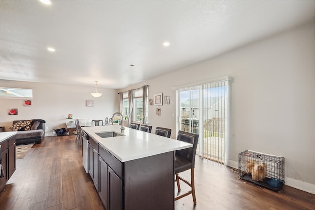 kitchen with a center island with sink, sink, a breakfast bar area, stainless steel dishwasher, and dark hardwood / wood-style floors