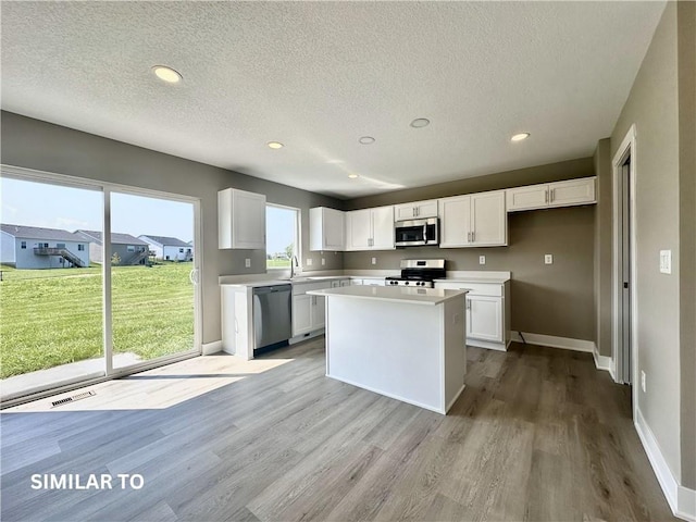 kitchen featuring a center island, white cabinets, stainless steel appliances, and light hardwood / wood-style flooring