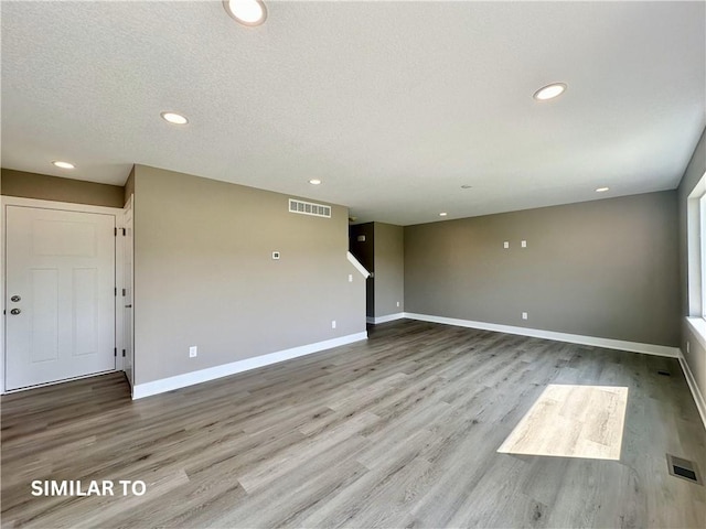 unfurnished living room with a textured ceiling and light wood-type flooring