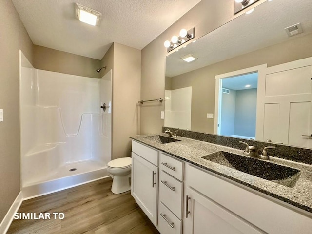 bathroom featuring a textured ceiling, vanity, a shower, wood-type flooring, and toilet