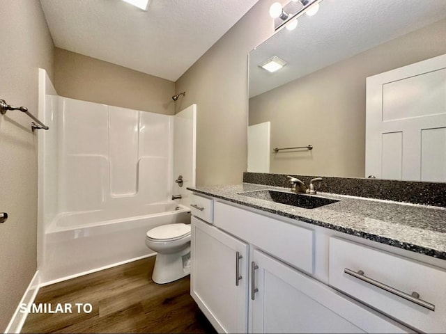 full bathroom with vanity, hardwood / wood-style flooring, toilet, a textured ceiling, and tub / shower combination