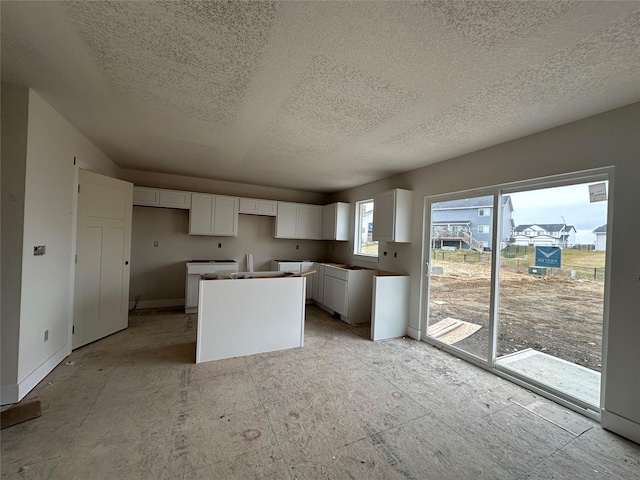 kitchen with a textured ceiling, white cabinetry, and a kitchen island