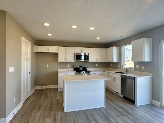 kitchen with a sink, stainless steel appliances, light wood-style flooring, and white cabinetry