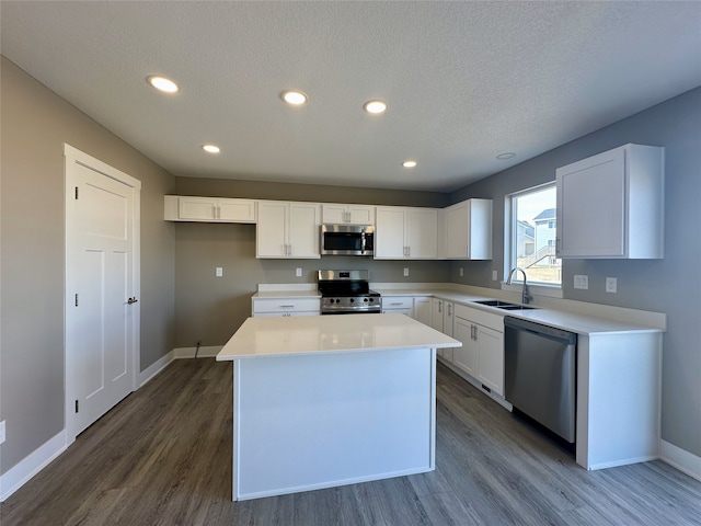 kitchen featuring a sink, dark wood-style floors, white cabinetry, appliances with stainless steel finishes, and baseboards