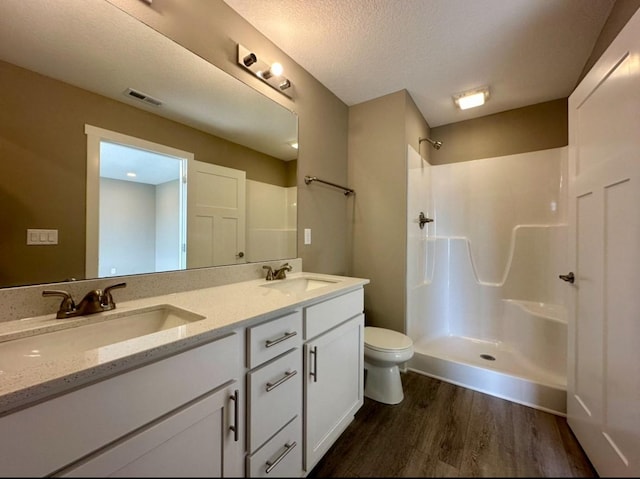 full bath with wood finished floors, visible vents, a sink, walk in shower, and toilet