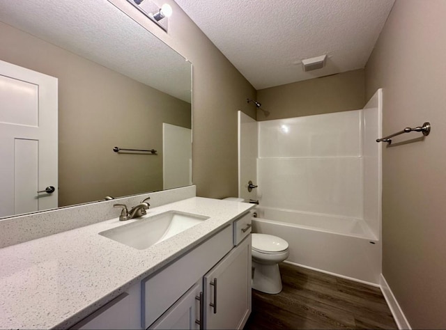 bathroom with vanity, wood finished floors, a textured ceiling, shower / bathing tub combination, and toilet