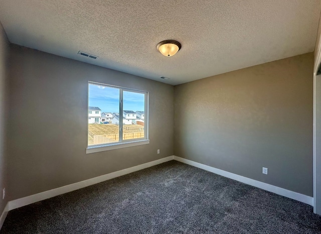 spare room with baseboards, visible vents, dark carpet, and a textured ceiling