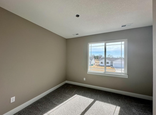 unfurnished room featuring dark colored carpet, visible vents, baseboards, and a textured ceiling