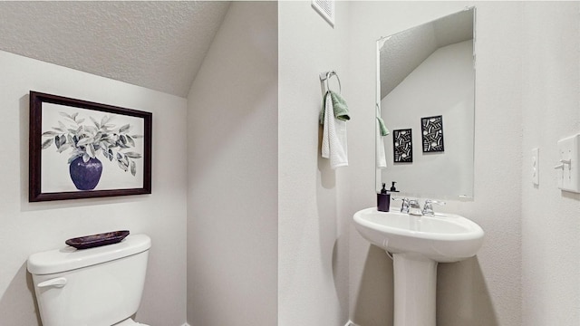 bathroom featuring lofted ceiling, toilet, and a textured ceiling