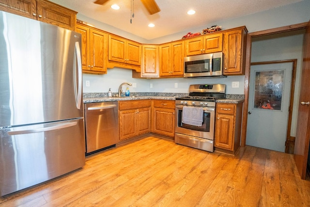 kitchen featuring light stone countertops, stainless steel appliances, sink, and light hardwood / wood-style flooring