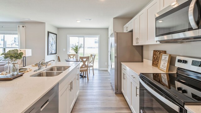 kitchen with a healthy amount of sunlight, sink, white cabinetry, and appliances with stainless steel finishes