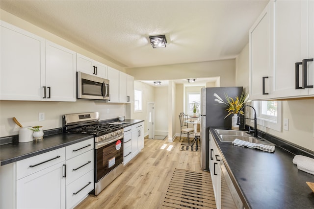 kitchen featuring white cabinetry, light wood-type flooring, appliances with stainless steel finishes, and sink