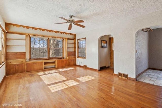 unfurnished living room featuring ceiling fan, light hardwood / wood-style floors, and a textured ceiling