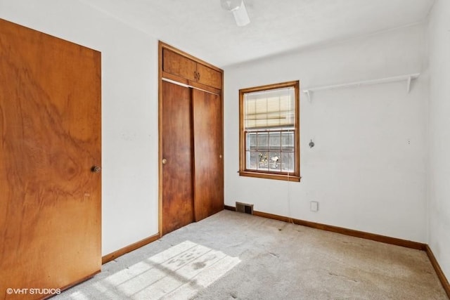 unfurnished bedroom with light colored carpet, a closet, and ceiling fan