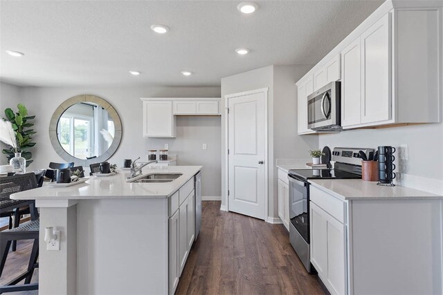 kitchen featuring dark wood finished floors, white cabinets, appliances with stainless steel finishes, a sink, and recessed lighting