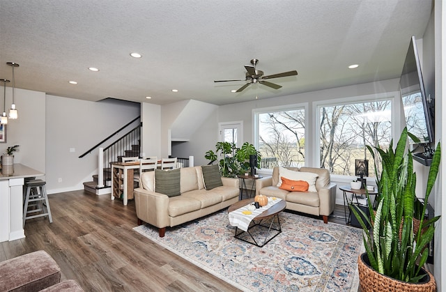 living room with a textured ceiling, dark wood-type flooring, and ceiling fan