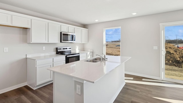 kitchen featuring sink, dark wood-type flooring, stainless steel appliances, white cabinets, and a center island with sink