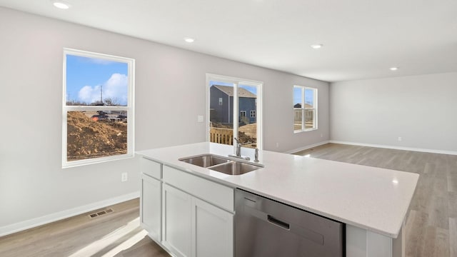 kitchen with white cabinetry, dishwasher, sink, an island with sink, and light hardwood / wood-style floors