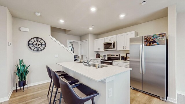 1007 Daisy Ln, Waukee, IA 50263 - kitchen with a breakfast bar, sink, white cabinetry, a kitchen island with sink, and stainless steel appliances