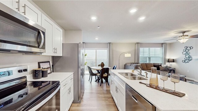 1007 Daisy Ln, Waukee, IA 50263 - kitchen with ceiling fan, sink, white cabinetry, light wood-type flooring, and appliances with stainless steel finishes
