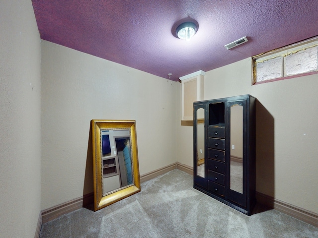 unfurnished bedroom featuring a textured ceiling and light carpet