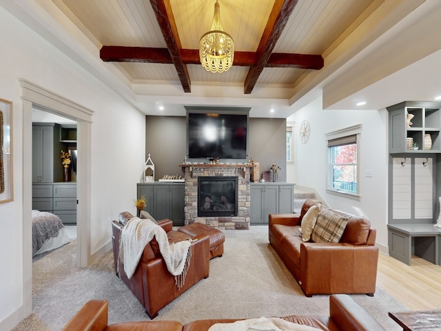 carpeted living room with a stone fireplace, beamed ceiling, wooden ceiling, and an inviting chandelier