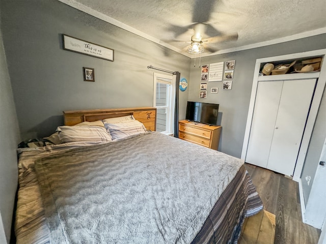 bedroom with ceiling fan, dark hardwood / wood-style floors, a textured ceiling, and a closet