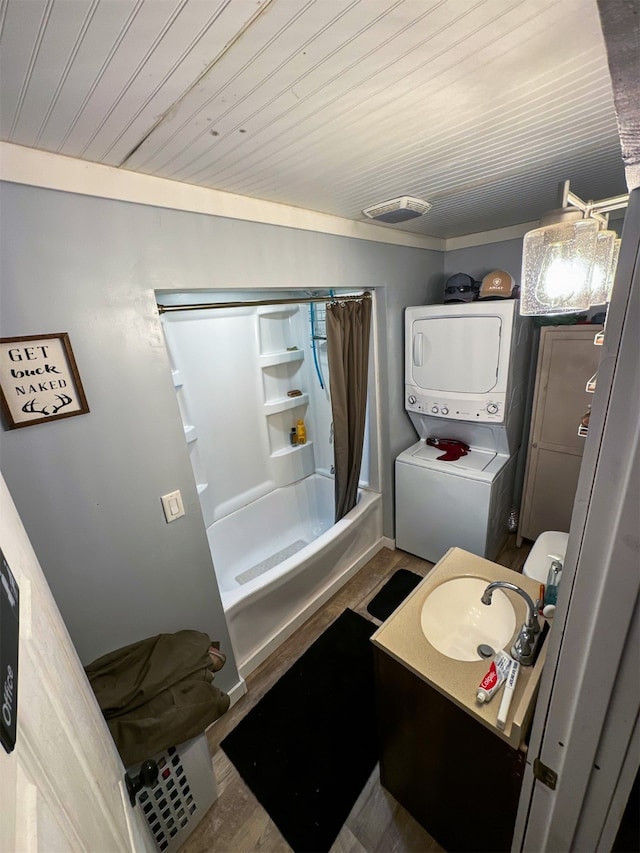 bathroom with hardwood / wood-style floors, vanity, ornamental molding, shower / tub combo with curtain, and stacked washer / drying machine