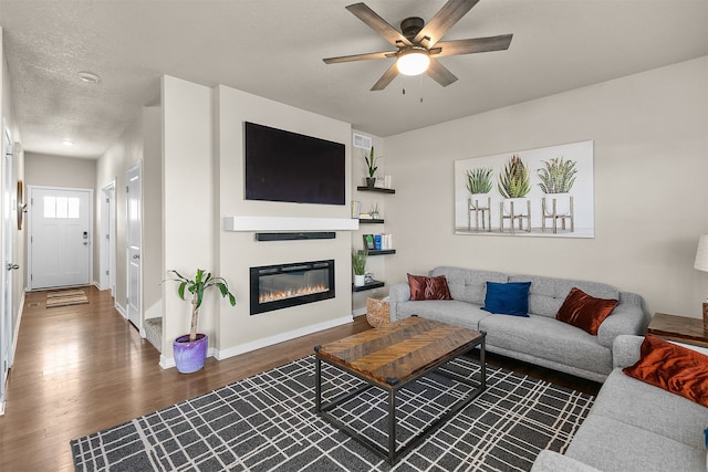 living room featuring dark wood-type flooring, a textured ceiling, and ceiling fan