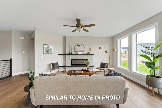 living area with a premium fireplace, baseboards, and wood finished floors