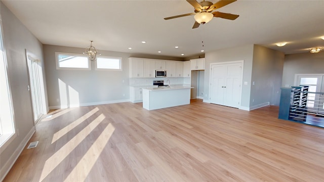 kitchen with backsplash, open floor plan, light wood-style flooring, and stainless steel appliances