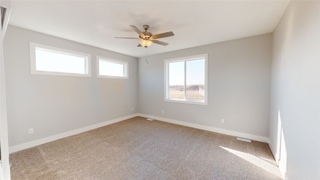 carpeted empty room featuring baseboards and ceiling fan