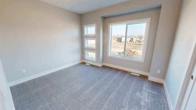 spare room with visible vents, baseboards, and dark carpet