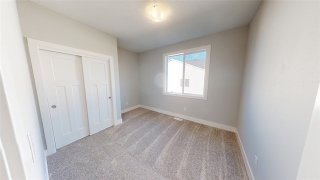 unfurnished bedroom with a closet, baseboards, and carpet