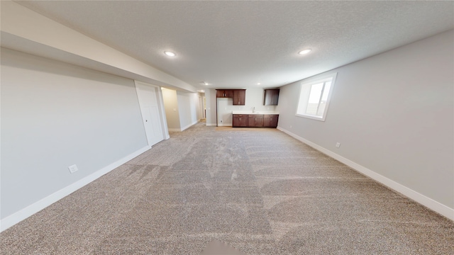 below grade area featuring recessed lighting, light colored carpet, a textured ceiling, and baseboards