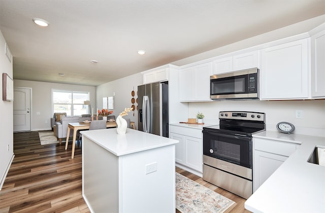 kitchen featuring dark wood-type flooring, white cabinetry, appliances with stainless steel finishes, and a center island