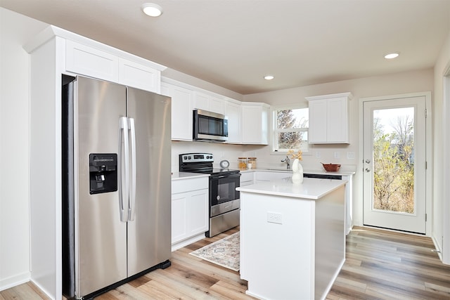 kitchen with stainless steel appliances, white cabinets, light hardwood / wood-style flooring, and a center island