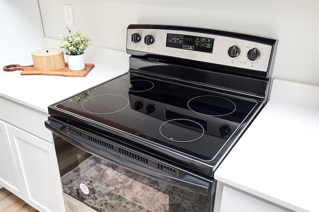 room details with white cabinetry, hardwood / wood-style floors, and electric stove