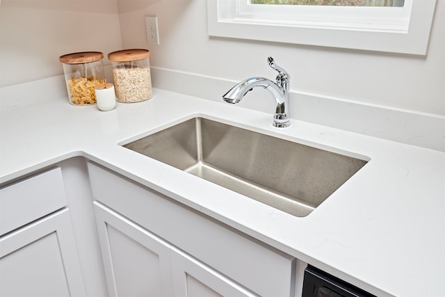 details with light stone countertops, sink, and white cabinets