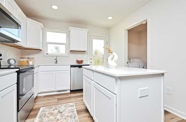 kitchen featuring white cabinetry, stainless steel appliances, a healthy amount of sunlight, and a center island