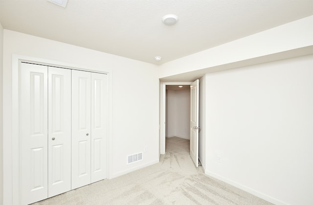 unfurnished bedroom with a closet, a textured ceiling, and light colored carpet