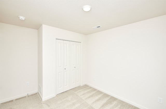 unfurnished bedroom featuring a closet and light carpet