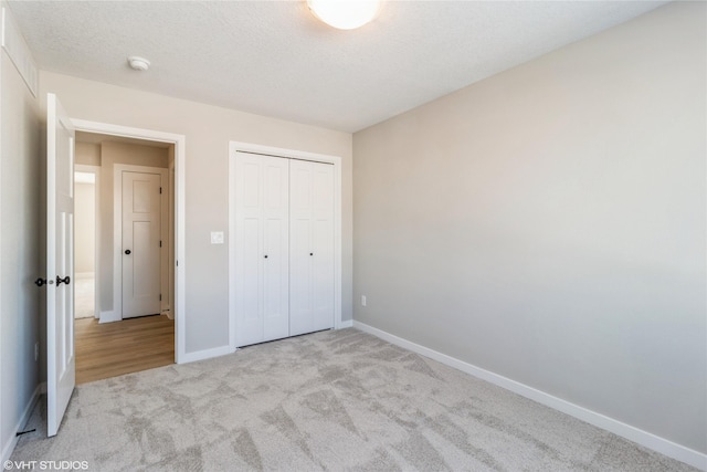 unfurnished bedroom with a textured ceiling, a closet, carpet, and baseboards