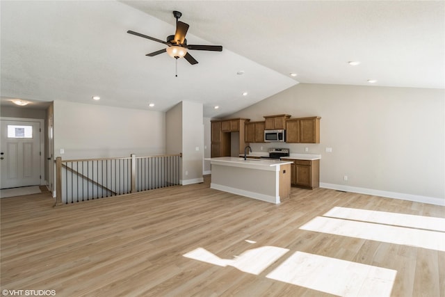 kitchen with brown cabinets, appliances with stainless steel finishes, open floor plan, and a sink